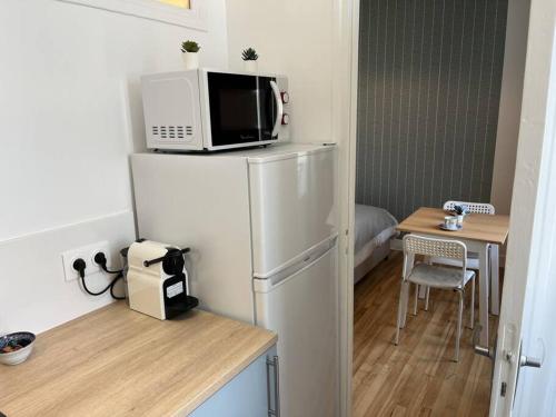 a kitchen with a refrigerator with a microwave and a table at Studio number 7 in Pantin
