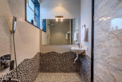 a bathroom with a sink and a shower with a mirror at SaffronStays Ivory Mansion in Pen