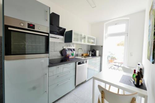 a white kitchen with white appliances and a table at Altstadtjuwel am Hospitalplatz - 3 Zimmer mit Balkon in Erfurt