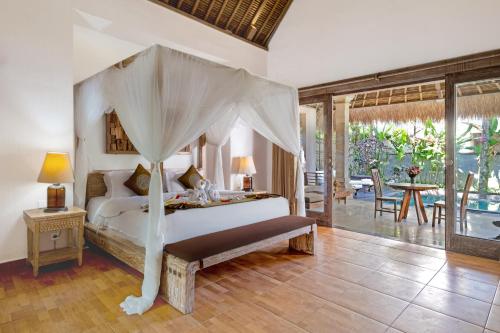 - une chambre avec un lit à baldaquin dans l'établissement The Kanjeng resort Ubud, à Ubud