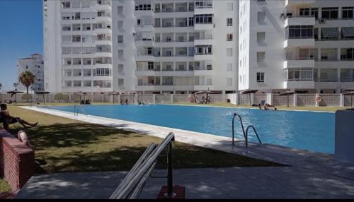 una gran piscina frente a algunos edificios en Apartamento en Valdelagrana en primera línea de playa, en El Puerto de Santa María