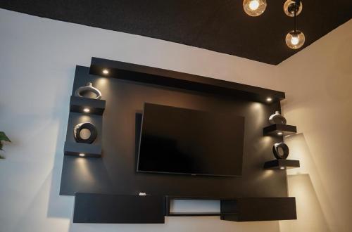 TV de pantalla plana en una pared con 2 altavoces en North Breeze Guest House en Levittown