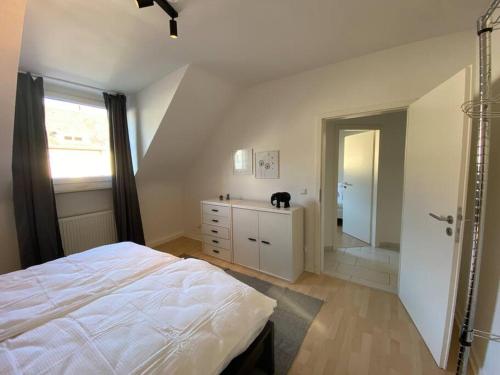 a bedroom with a white bed and a bathroom at Ruhiges DG - 6 P. - urban - ÖPNV in Cologne