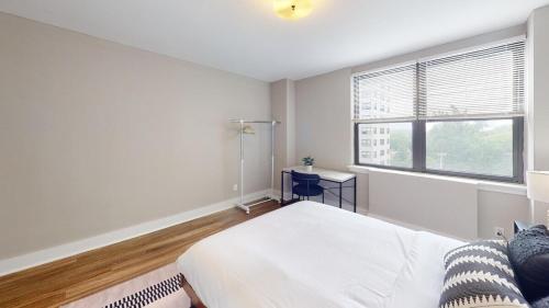 a white bedroom with a bed and a window at Comfy 1br! Parkingpoolgym I Ave in Philadelphia