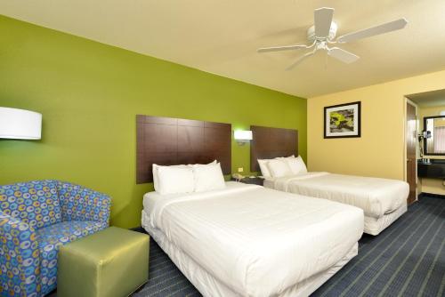 una habitación de hotel con 2 camas y una silla en Quality Inn - Needles, en Needles
