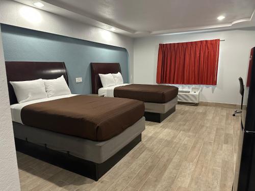 a hotel room with two beds and a red curtain at Executive Inn in Hobbs