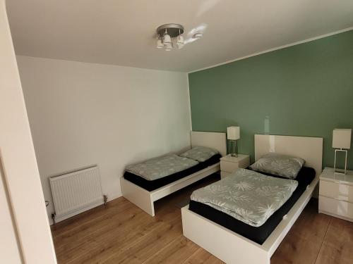 2 letti in una camera con pareti verdi e pavimenti in legno di Terrassenwohnung in Siegburg a Siegburg