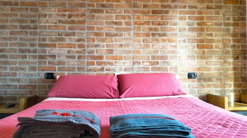 een slaapkamer met een roze bed met een bakstenen muur bij Athena soggiorno in San Piero a Sieve