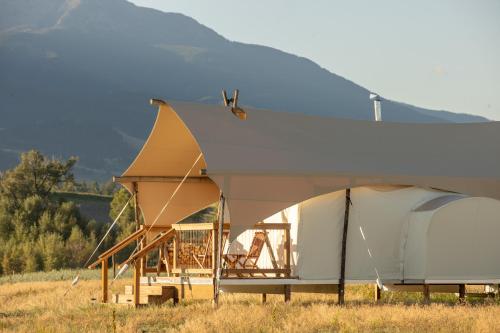 a tent in a field with a mountain in the background at Under Canvas North Yellowstone - Paradise Valley in Livingston