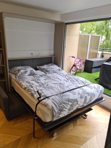 un lit dans une chambre avec une grande fenêtre dans l'établissement Studio à La Défense (climatisé, parking), à Courbevoie