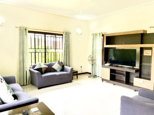 uma sala de estar com um sofá e uma televisão de ecrã plano em Aspen Luxury Villa em Acra
