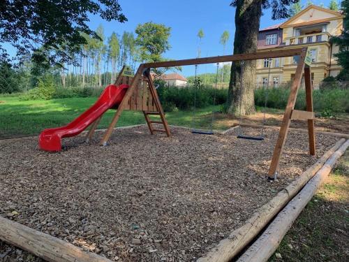 a playground with a red slide in a park at Zámeček Waldsteinovo Zátiší in Svatoslav