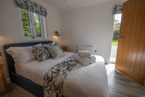 1 dormitorio con 1 cama con sábanas y almohadas blancas en Olverstone Lodge, a beautiful Cornish lodge with wood burner & garden, en St Austell