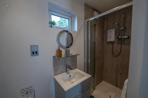 a bathroom with a sink and a shower and a mirror at Olverstone Lodge, a beautiful Cornish lodge with wood burner & garden in St Austell