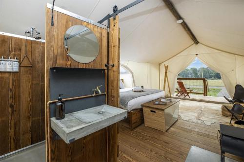 a bathroom with a sink and a bed in a tent at Under Canvas North Yellowstone - Paradise Valley in Livingston