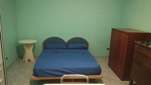 een slaapkamer met een bed met blauwe lakens en een tafel bij Casa Auricchio in Terzigno