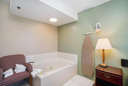 a bathroom with a tub and a chair and a table at Super 8 by Wyndham Mt. Pleasant in Mount Pleasant