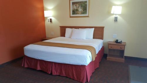a hotel room with a large bed and a night stand at Travelodge by Wyndham Lubbock in Lubbock