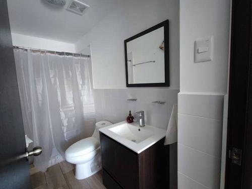 Un baño blanco con inodoro y lavabo. en Guatemala, departamento ciudad capital zona 12., en Guatemala
