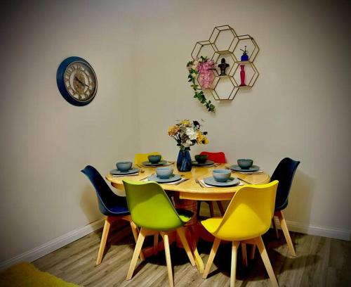 a dining room table with chairs and a clock on the wall at 4 Bedroom House -Sleeps 10- Big Savings On Long Stays! in Canterbury