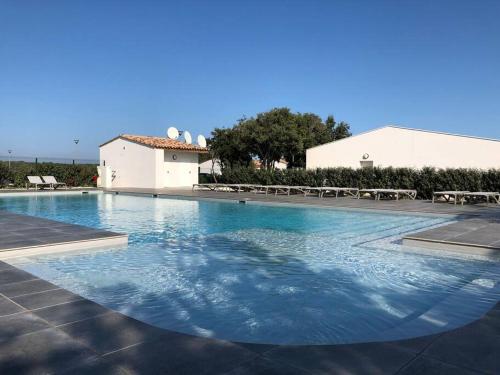 une grande piscine d'eau bleue en face d'un bâtiment dans l'établissement Villa Noelly - Résidence les Hauts de Bonifacio, à Bonifacio