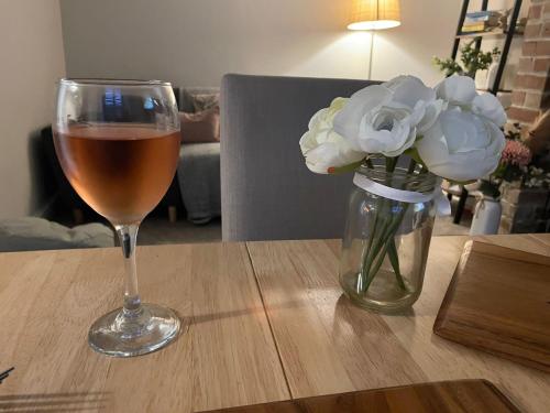 a glass of wine and a vase of flowers on a table at Cosy 2 bedroom cottage in Llanuwchllyn