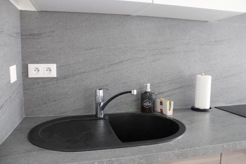 a black sink in a bathroom with a candle at Appartement confortable avec parking privé in Schiltigheim