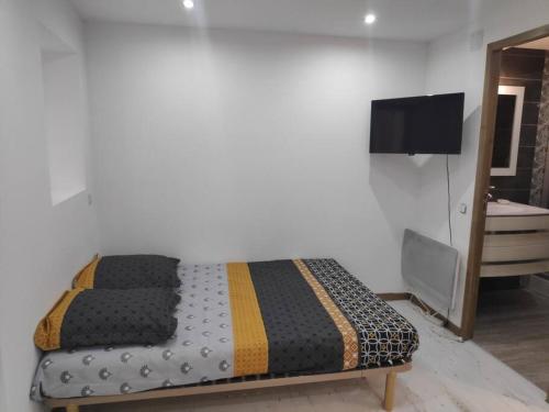 a bedroom with a bed and a tv on a wall at Studio Indépendant dans Maison de Village in Alignan-du-Vent