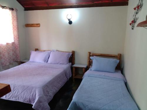 2 camas en una habitación con sábanas moradas en Chalé da Flor, en Visconde De Maua