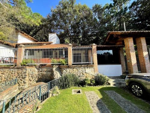 a brick house with a fence and a driveway at Cabaña Ledesma in Mazamitla
