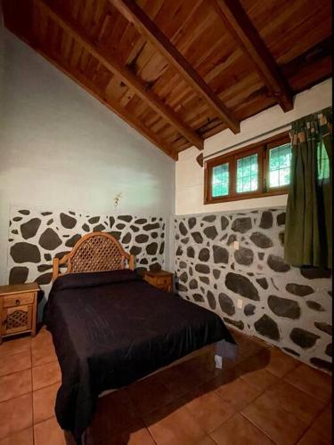 a bedroom with a bed in a room with rocks at Cabaña la Toscana in Mazamitla