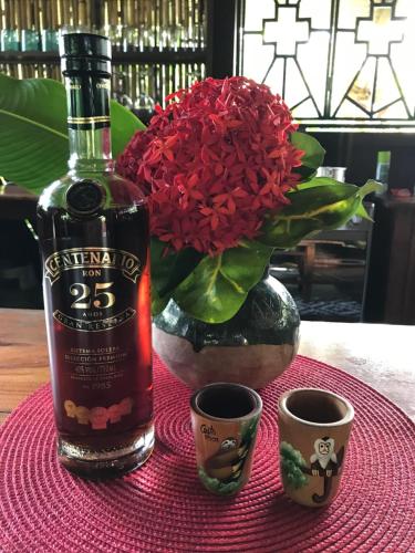 a bottle of wine sitting next to a vase with a flower at Casa Kumbaya Costa Rica in Cabo Matapalo