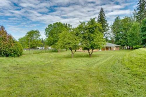 un gran patio con dos árboles y una casa en Large rustic home w private hot tub, property, lots of parking and easy commute en Battle Ground