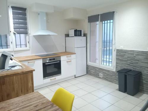 a kitchen with white appliances and a yellow chair in it at Appartement en RDC in Argelès-sur-Mer