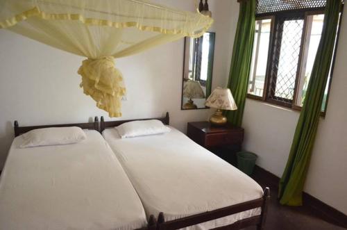 - une chambre avec un lit à baldaquin et des fenêtres dans l'établissement Kandy Inn Madugalle’s family guest house, à Kandy