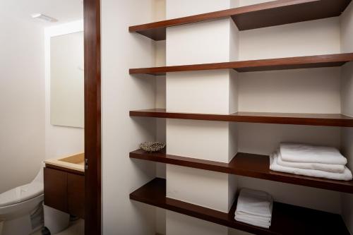 a bathroom with wooden shelves and a toilet at Aloja oceanview in the Hotel Zone in Cancún