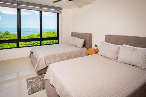two beds in a room with a view of the ocean at Aloja oceanview in the Hotel Zone in Cancún