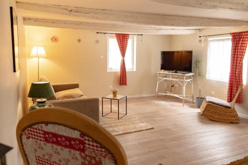 ein Wohnzimmer mit einem Sofa und einem TV in der Unterkunft Gîte indépendant - Bretzel et Bergamote in Richtolsheim