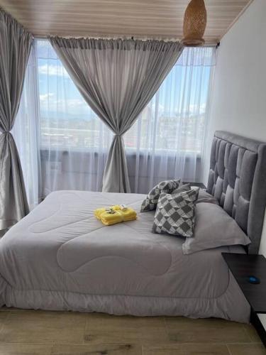 1 cama con 2 almohadas amarillas y ventana en Cómodo apto sector universitario, en Manizales