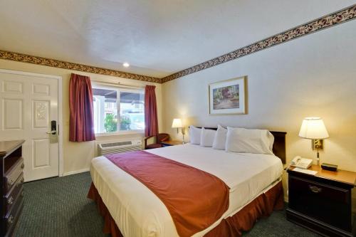 a hotel room with a large bed and a telephone at Americas Best Value Inn - Sky Ranch Palo Alto in Palo Alto
