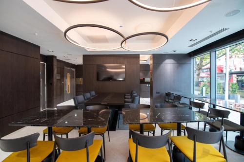 a dining room with black tables and yellow chairs at Signature London, The J Marylebone in London