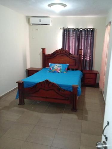 Schlafzimmer mit einem Holzbett mit blauer Bettwäsche und Vorhängen in der Unterkunft Casa boca chica in Boca Chica