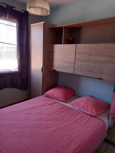 1 dormitorio con cama con sábanas rosas y ventana en Le Mieukerien, Réserve africaine 15 mn et plage 200 m, en Port-la-Nouvelle