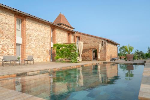 une piscine devant un bâtiment en briques dans l'établissement ESCONS DOMAINE DE CHARME, à Saint-Sulpice-sur-Lèze