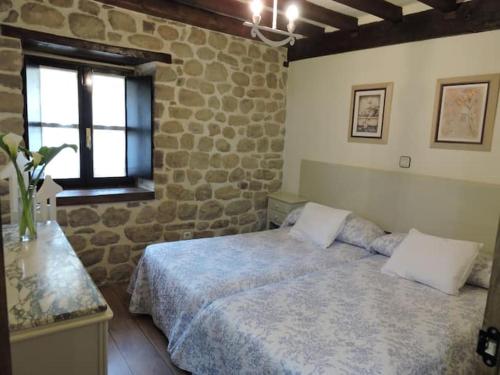 1 dormitorio con cama y pared de piedra en Casa rural La Bárcena Saja, 