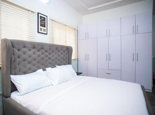 a bedroom with a large bed with white cabinets at House 55 Apartments in Abuja