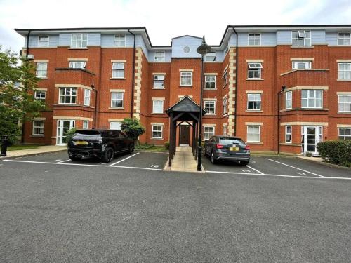 a large red brick building with cars parked in a parking lot at Spacious Apartment, Near Birmingham Centre + NEC in Birmingham