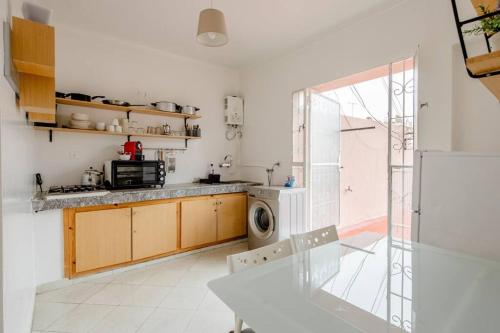 a white kitchen with a table and a microwave at Appartement Arribat Center Mall-Grande Terasse in Rabat
