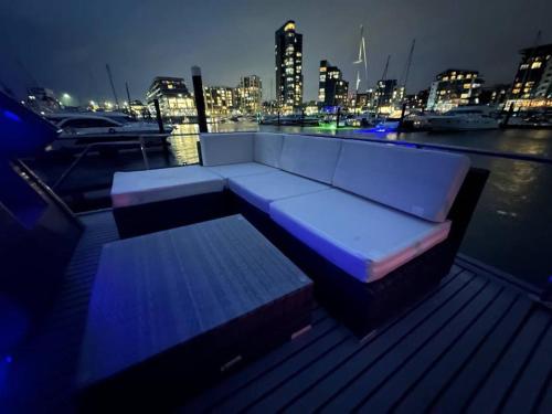 a white couch sitting on a dock near the water at night at YACHT "X" - 44 FOOT MODERN YACHT ON 5 STAR OCEAN VILLAGE MARINA - minutes away from city centre and cruise terminals, Free parking ,SPA package available! in Southampton