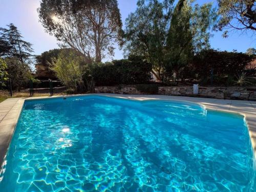 une piscine avec de l'eau bleue dans une cour dans l'établissement Grand Mas provençal, mer à 200m, parking privé fermé, piscine chauffée, à Sainte-Maxime